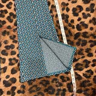 Blue textured fabric on a leopard print background with a measuring tape.