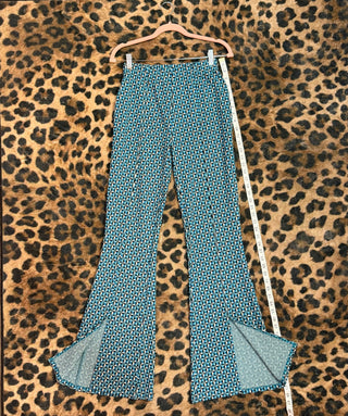 Teal patterned pants on a hanger against a leopard print background