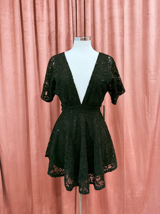 Black lace dress on a mannequin against a pink curtain background