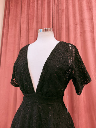Black lace dress on a mannequin against a pink curtain background