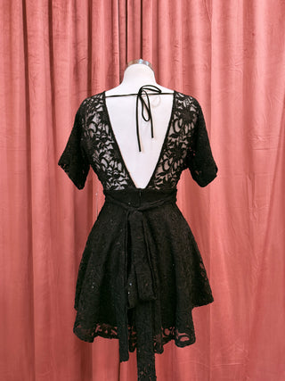 Black lace dress on a mannequin against a pink curtain background