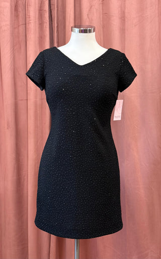 Black dress on a mannequin against a pink curtain background