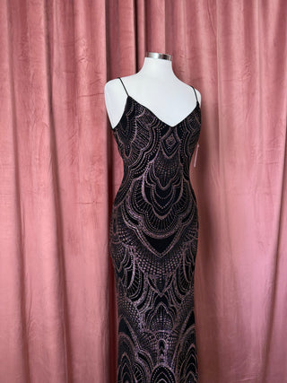 Black beaded evening gown on a mannequin against a pink curtain background