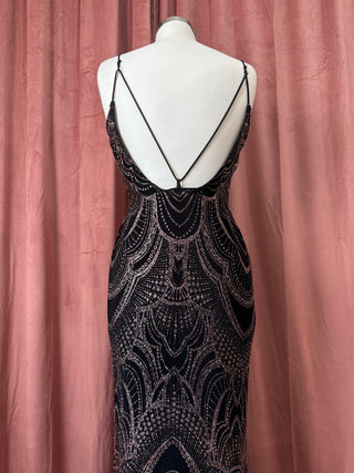 Black beaded evening gown on a mannequin against a pink curtain background