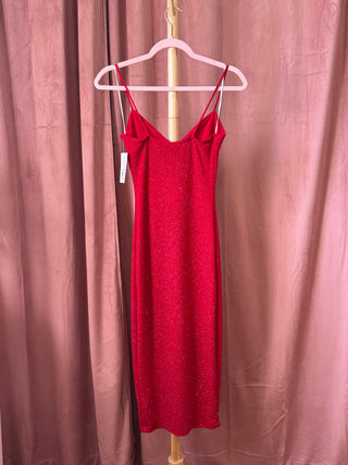Red dress on a hanger against a pink curtain background
